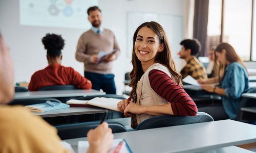 Happy college student during a lecture in the classroom looking at camera.
